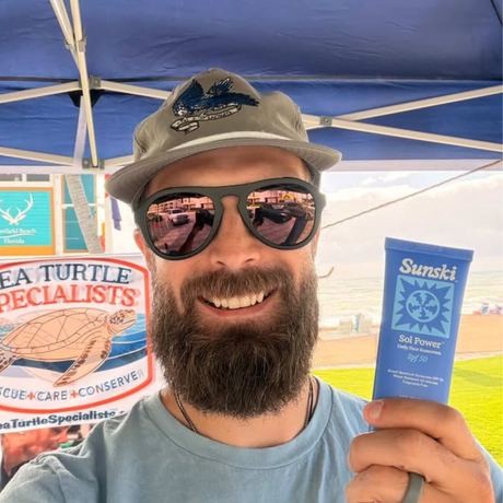 Man holding a Sunski Sol Power under a blue tent