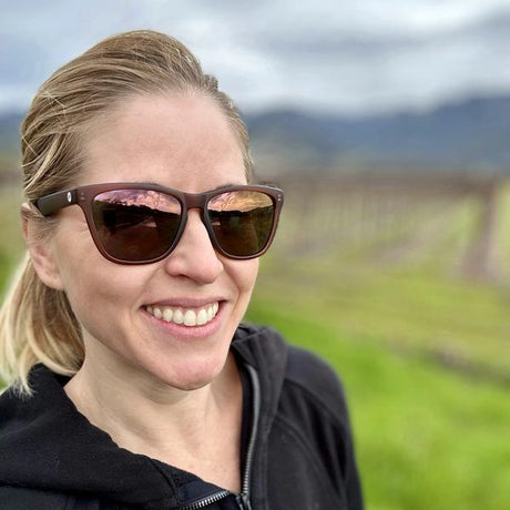 Woman wearing sunglasses with a blurred vineyard background