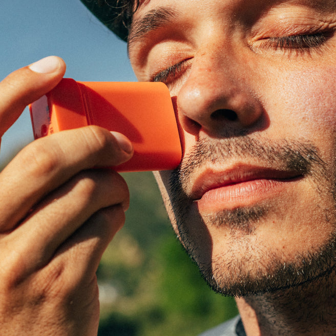 Hot Block SPF 50 Sunscreen - 0.53 oz / 15 g - Man using an orange asthma inhaler with a blurred natural background