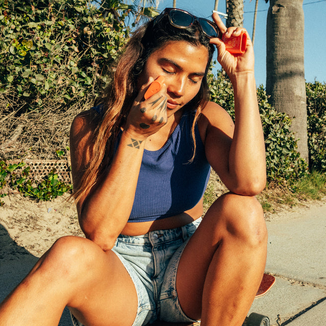 Hot Block SPF 50 Sunscreen - 0.53 oz / 15 g - Woman applying sunscreen outdoors with palm trees in the background
