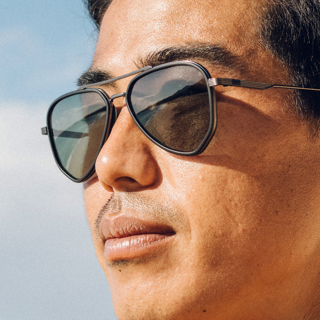 Close-up of a person wearing sunglasses with a clear sky background