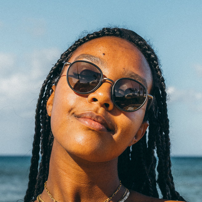 Woman wearing sunglasses with a clear blue sky and ocean background