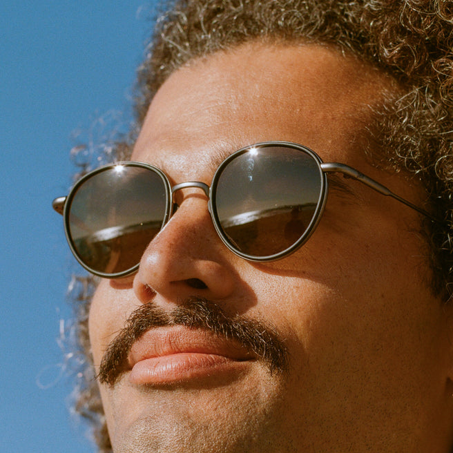 Close-up of a person wearing sunglasses with a clear blue sky background
