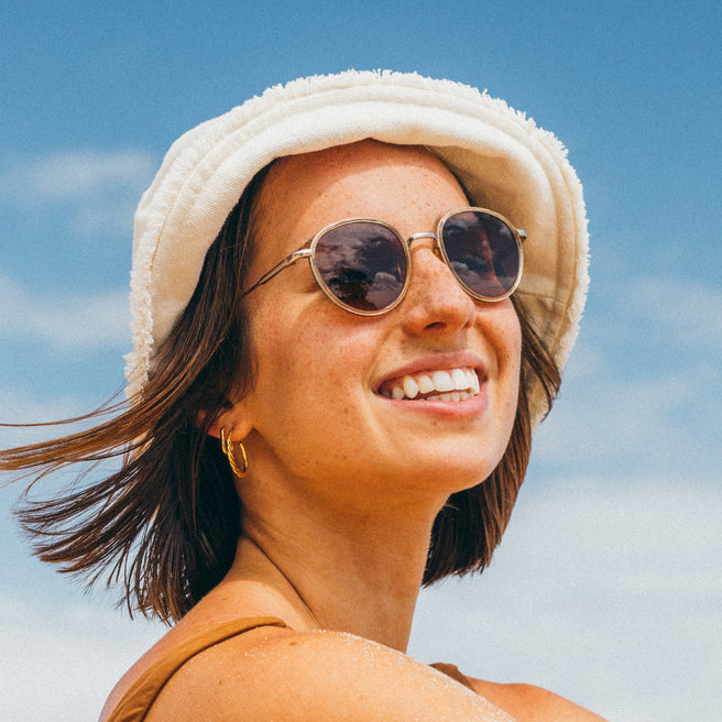 Woman wearing a white hat and sunglasses with a clear blue sky background