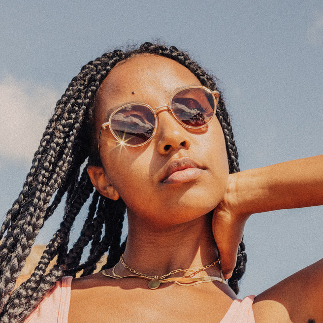Woman with braided hair wearing sunglasses against a clear sky