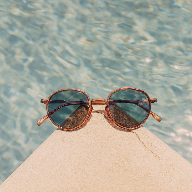 Sunglasses on a rock with water in the background