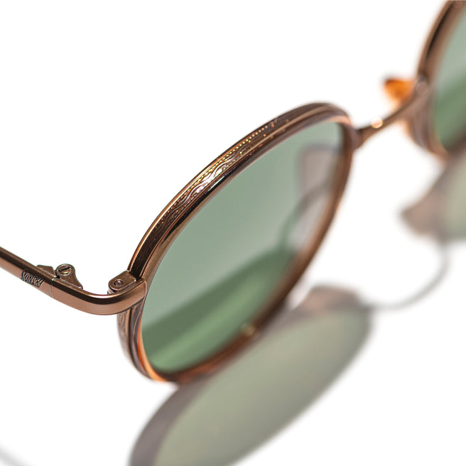 Sunglasses with gold frame and green lenses on a white background