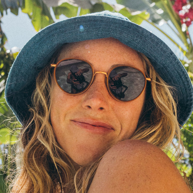 Person wearing a blue hat and sunglasses with a blurred natural background