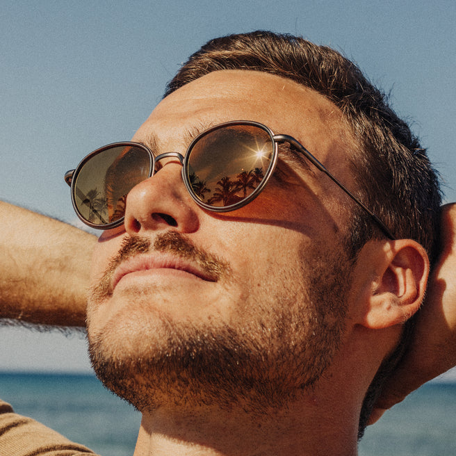 Man wearing sunglasses with a clear blue sky and ocean background