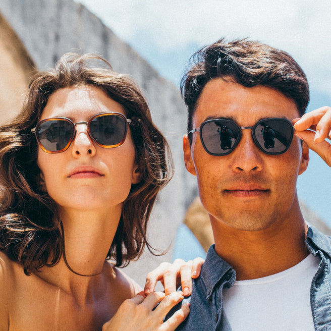 Two people wearing sunglasses outdoors with a clear sky background