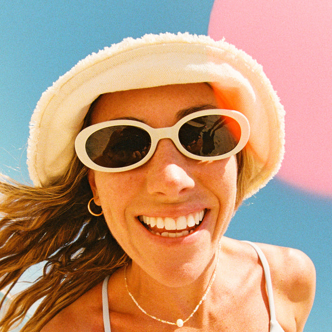 Woman wearing a straw hat and sunglasses with a blue sky background