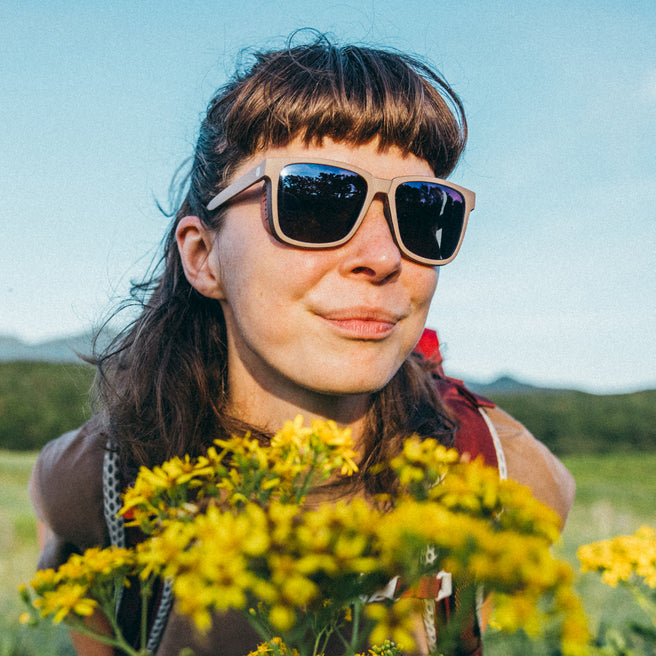 Person wearing sunglasses with a field of yellow flowers in the foreground