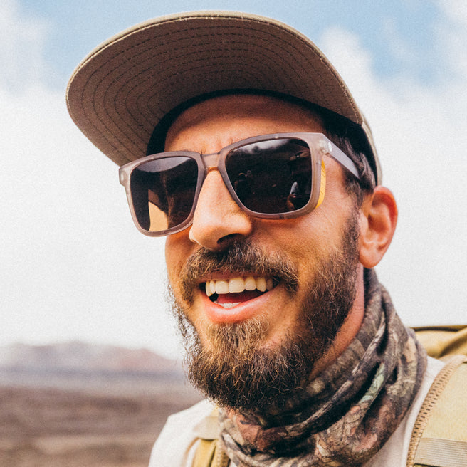 Man wearing sunglasses and a cap with a blurred natural background
