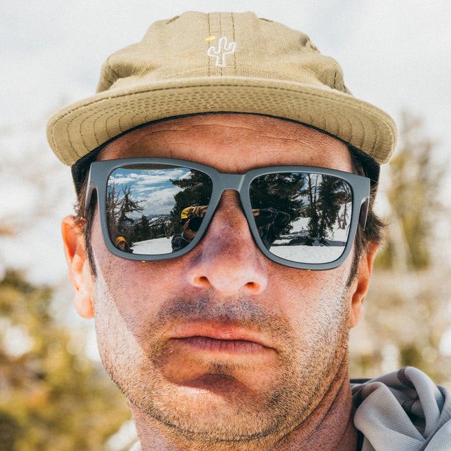 Man wearing sunglasses and a cap with a blurred outdoor background