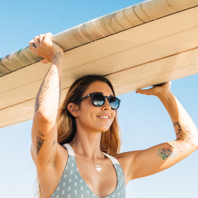 Woman holding a surfboard with a clear blue sky background