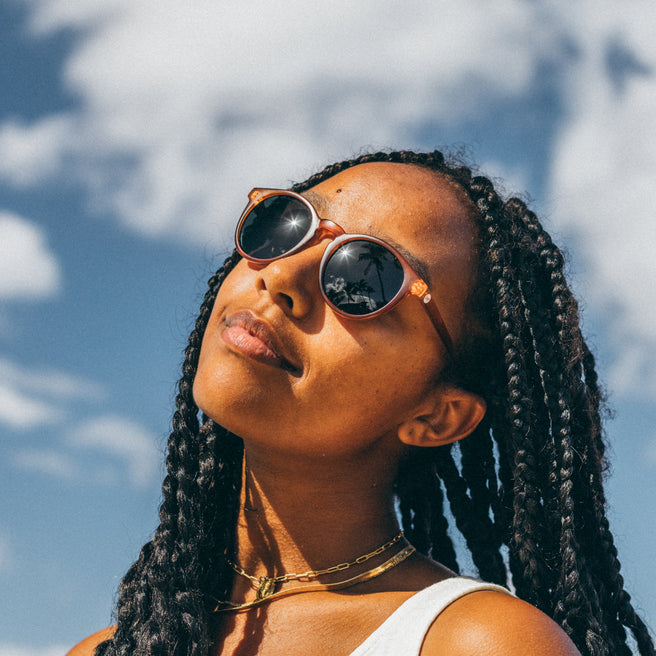 Woman wearing sunglasses with a blue sky and clouds in the background
