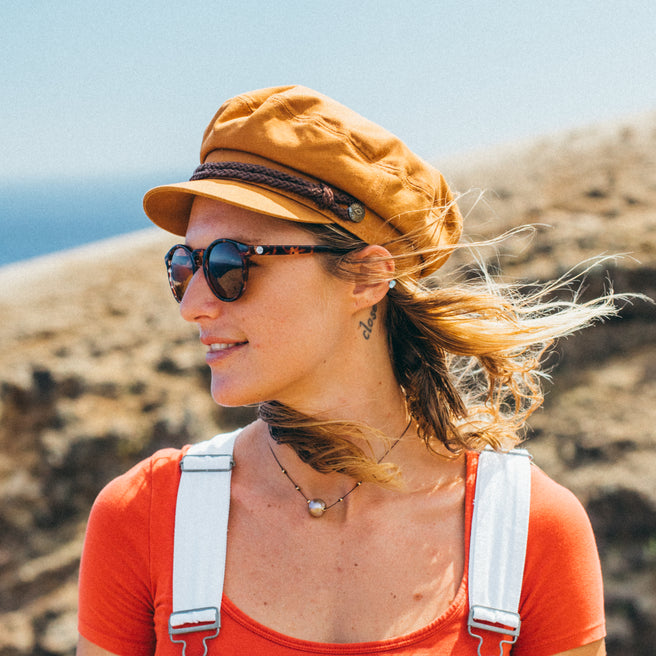 Woman wearing a yellow cap and sunglasses with a scenic background