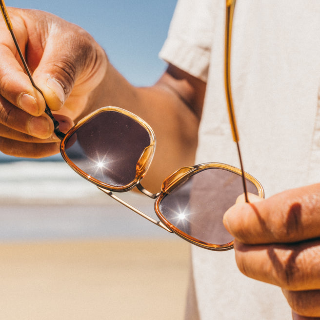 Person holding a pair of sunglasses with a blurred background