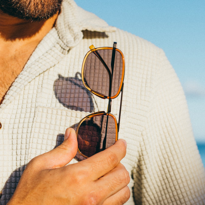 Person holding sunglasses with a blurred background
