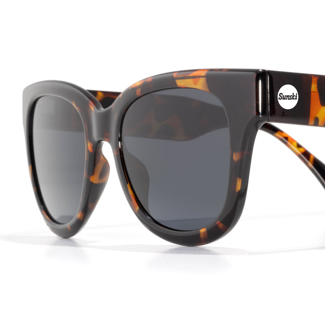 Sunglasses with tortoiseshell frame and dark lenses on a white background