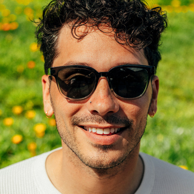 Man wearing sunglasses with a blurred green and yellow background