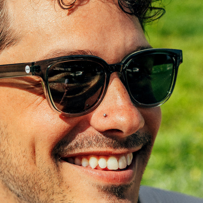 Close-up of a person wearing sunglasses with a blurred green background