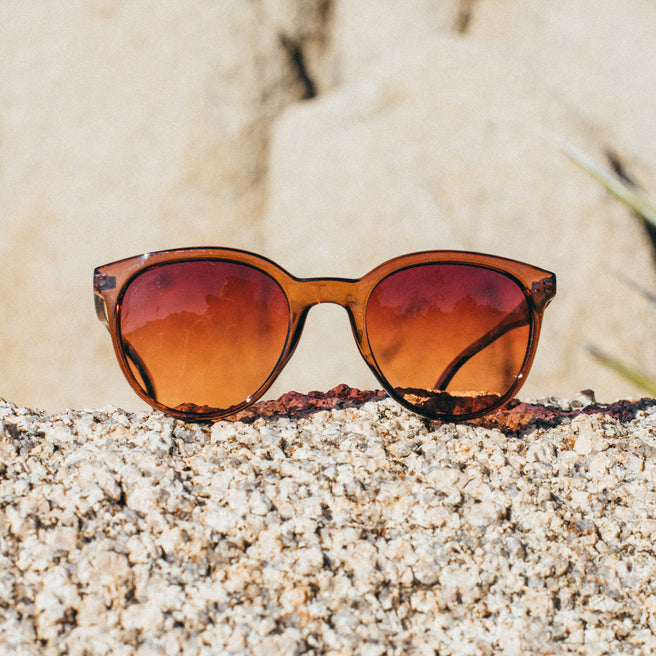 Sunglasses with orange lenses on a textured surface
