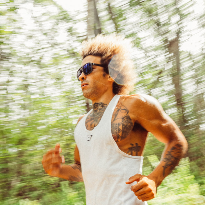 Man running outdoors in sunglasses with a blurred green background