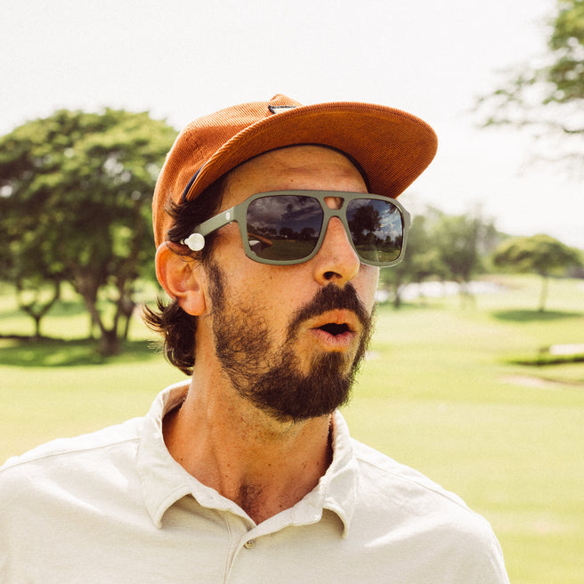 Man wearing sunglasses and a cap in a park setting