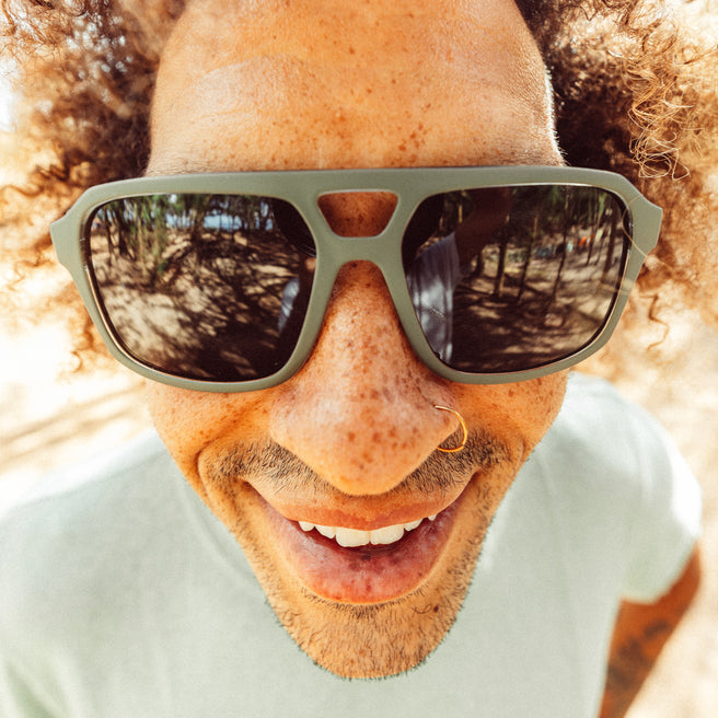 Close-up of a person wearing sunglasses with a blurred natural background