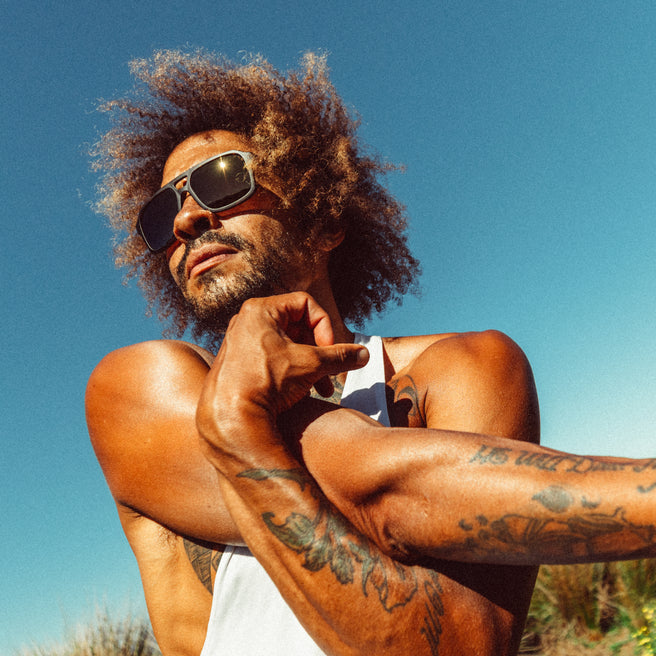 Man with tattoos and sunglasses against a clear blue sky