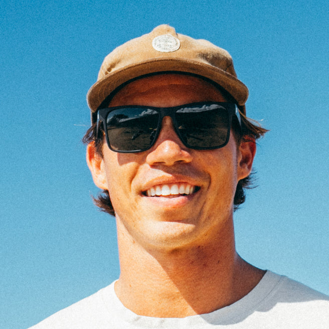 Man wearing sunglasses and a cap against a clear blue sky