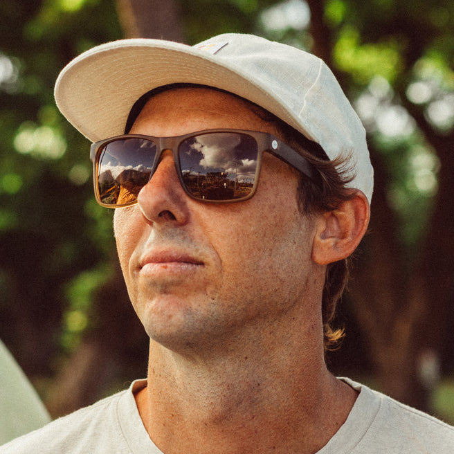 Man wearing sunglasses and a cap with a blurred green background