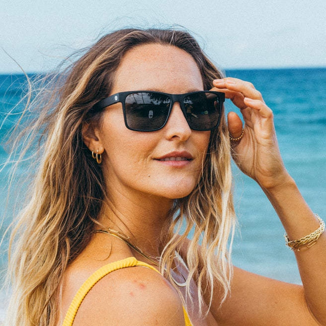 Woman wearing sunglasses with a beach background