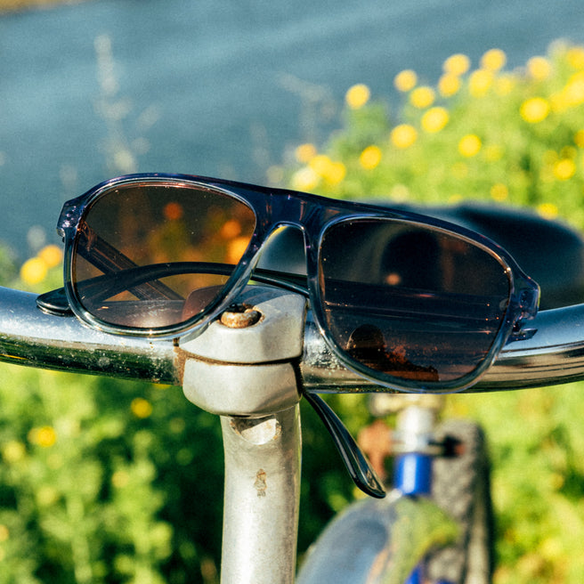Sunglasses on a bicycle handlebar with a blurred natural background