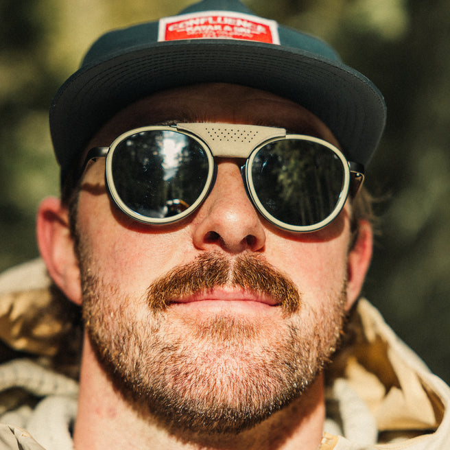 Man wearing sunglasses and a cap with a blurred natural background