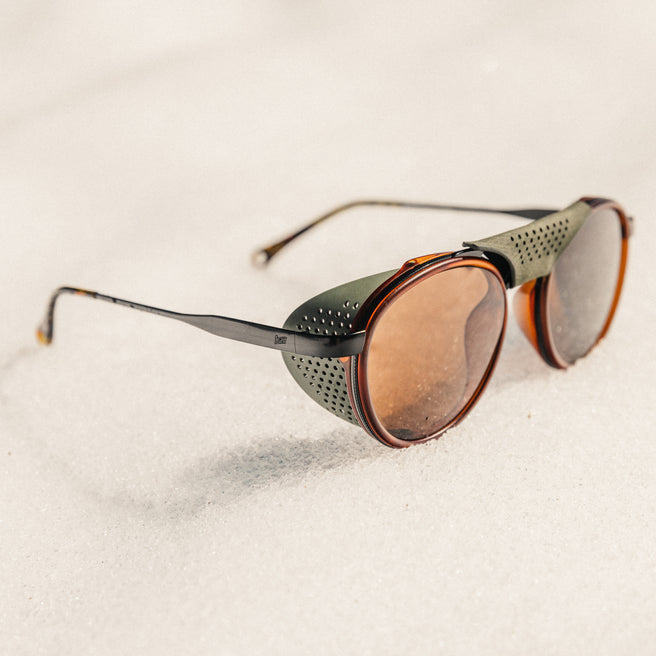 Sunglasses with brown lenses and black frames on a light beige background