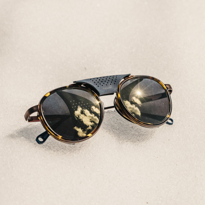 Round sunglasses with reflective lenses on a sandy background