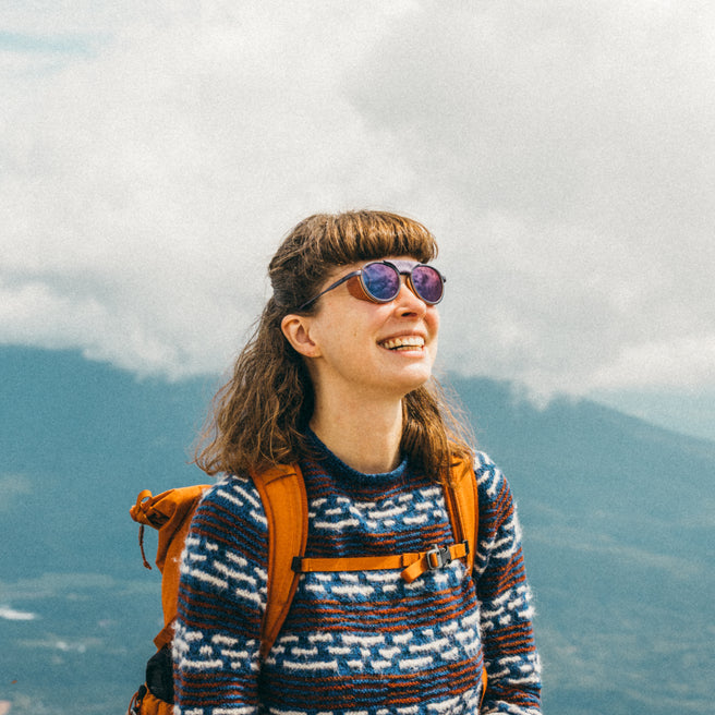 Person with sunglasses and backpack against a mountainous background