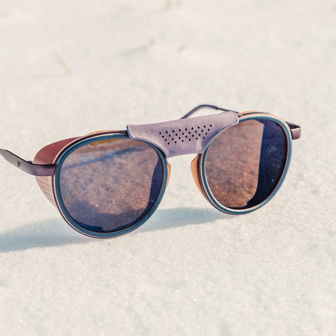 Sunglasses with reflective lenses on a textured white surface