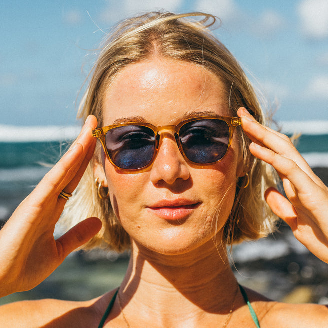 Woman wearing sunglasses with a blurred beach background