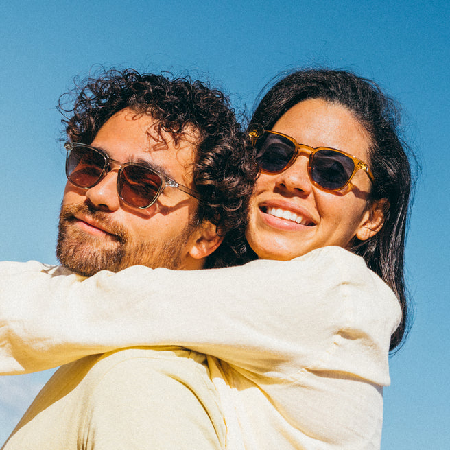Two people wearing sunglasses against a clear blue sky