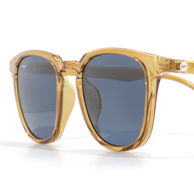 Sunglasses with amber frame and dark lenses on a white background
