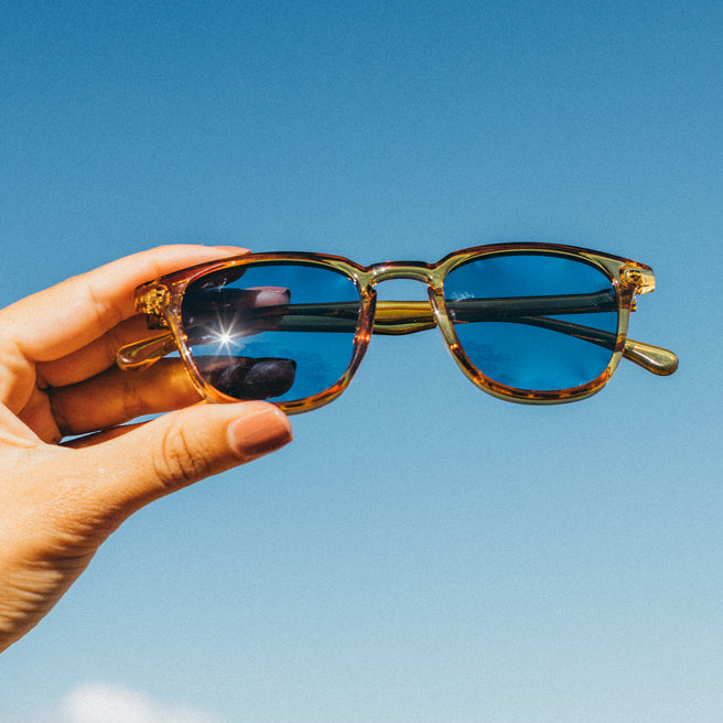 Sunglasses held against a clear blue sky