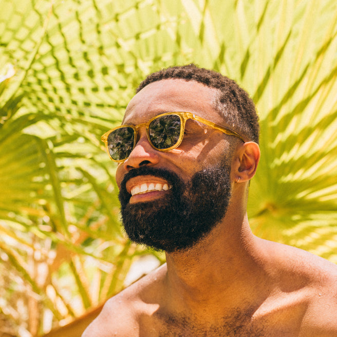 Man wearing sunglasses with a tropical background