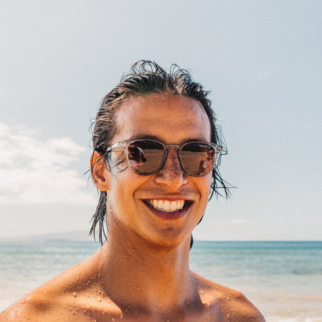 Man with sunglasses and wet hair standing on a beach