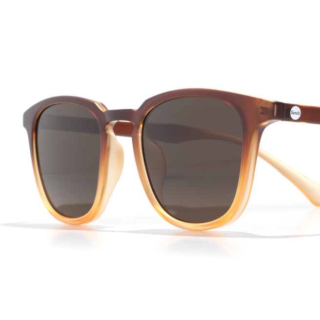 Sunglasses with brown frame and dark lenses on a white background