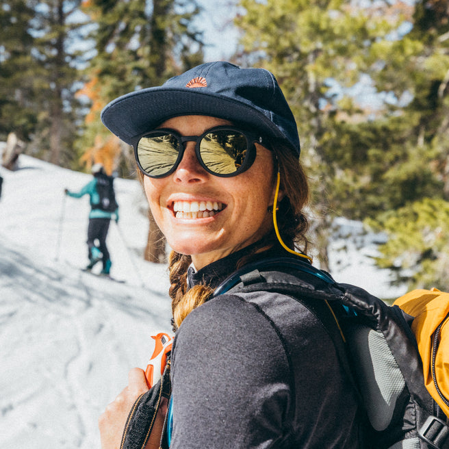 Person hiking in a snowy landscape with trees and another person in the background.