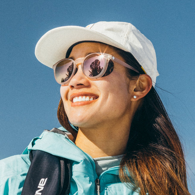 Woman wearing a white cap and sunglasses with a clear blue sky background