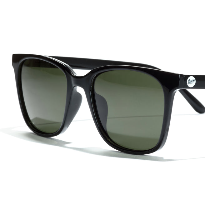 Black sunglasses with green lenses on a white background